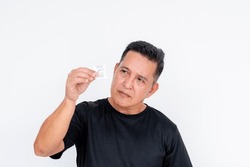 An Asian Man Inspects A Small Packet Of Silica Gel.Isolated On A White Background.
