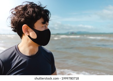 Asian Man Jogging On The Beach With Mask In Summer Morning.