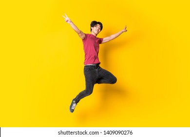 Asian man jumping over isolated yellow wall - Shutterstock ID 1409090276