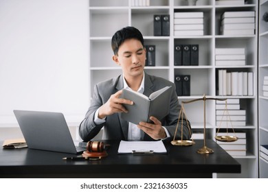 Asian man lawyer reading legal book with gavel on desk in office. justice and law ,attorney concept. - Shutterstock ID 2321636035