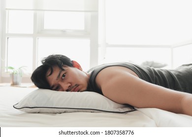Asian man lie down on comfortable white bed as he exhausted.