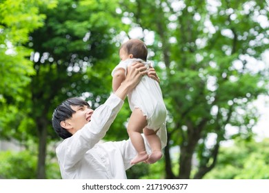 Asian Man Lifting Up A Baby. Child Rearing. Parenting. Newborn.