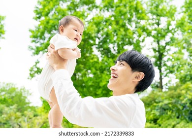 Asian Man Lifting Up A Baby. Child Rearing. Parenting. Newborn.