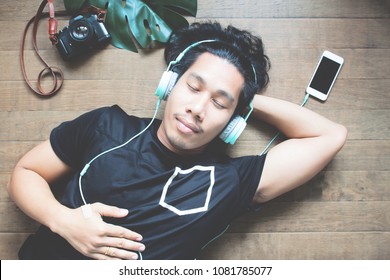 Asian Man Listening Music By Smartphone Lying Down With Camera On The Wooden Floor, Happy Life, Lifestyle