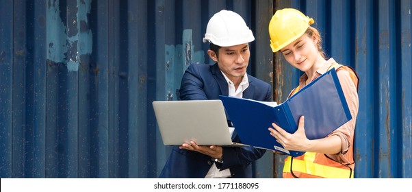 Asian Man Logistic Warehouse Foreman Using Laptop Checking List Of Container Boxes From Cargo With Woman Worker Working On Document. Import Export Shipping Business. Planning And Strategy. Copy Space