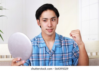 Asian Man Looking At His Face In Mirror