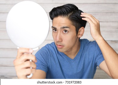 Asian Man Looking At His Hair In Mirror