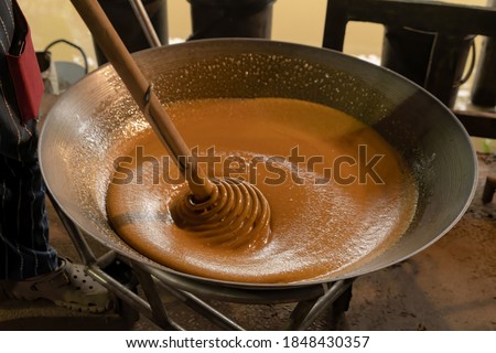 Asian man making boiled palm coconut sugar or cane production process, raw material, Amphawa, Thailand. Traditional culture lifestyle. Local sweet food. 
