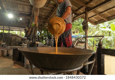 Asian man making boiled palm coconut sugar or cane production process, raw material, Amphawa, Thailand. Traditional culture lifestyle. Local sweet food. 