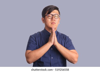 Asian Man Making Praying Posture With Glasses And Eyes Closed