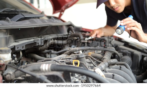 Asian Man\
mechanic inspection Shine a torch car engine checking bug in\
engine.red car for service maintenance insurance with car\
engine.for transport automobile\
automotive\
\
