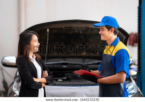 An asian man mechanic and woman customer\
discussing repairs done to her\
vehicle