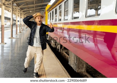Asian man missed train. Traveler man running after moving train from railway station. Unhappy traveler late and standing on railroad station. The concept of a man traveling alone. Traveling concept.