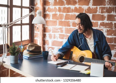 Asian Man Musician Writing Song With Guitar