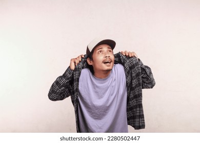 Asian man in net cap wearing checkered shirt showing shocked face with eyes looking at empty isolation area, advertising concept - Shutterstock ID 2280502447