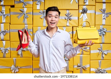 Asian Man Offers Purchase Options, Holding Shoes And Handbag In Hands