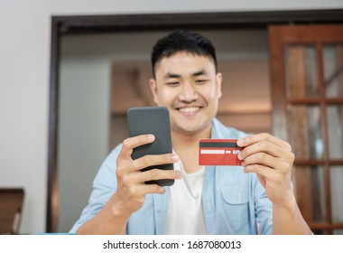 Asian Man Online Shopping With Credit Card And Mobile Phone At Home.digital Lifestyle With Technology