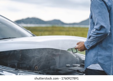 Asian Man Open Car Hood For Repair As Maintenance Service With Landscape Background Between Long Road Trip. Car Broken And Breakdown In Mountain Meadow With Wife. People And Transport Concept