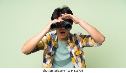 Asian Man Over Isolated Green Wall With Black Binoculars