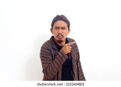 Asian man over isolated white background unhappy and pointing to the side