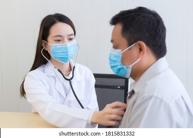 Asian man patient are checked up his health while a woman doctor use a stethoscope to hear heart rate of hims in Coronavirus pandemic By wearing a surgical mask at all times. Coronavirus protection. - Shutterstock ID 1815831332