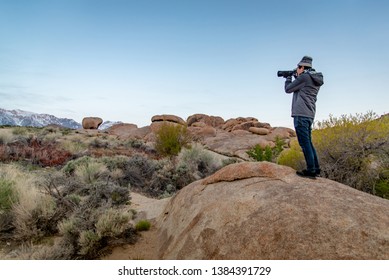 Asian Man Photographer And Tourist Holding DSLR Camera Taking Photo Of Abstract Rock Landscape At Alabama Hills, Lone Pine, California, USA. Travel Photography Concept