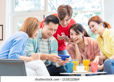 Asian Man Play Games On Smart Phone And Friends Are Happily