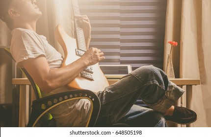 Asian Man Playing Electric Guitar For Relaxation In The Room