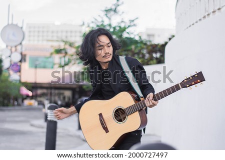 Asian man playing guitar music festival on street 