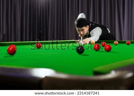 Asian man playing snooker, snookers club, Asian man playing snooker with selective focus on snooker ball and snooker ball movement.