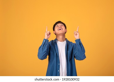 Asian Man Pointing His Finger To Look Up. On Orange Background