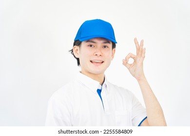 Asian man with the polo shirt and a cap OK gesture in white background - Shutterstock ID 2255584809