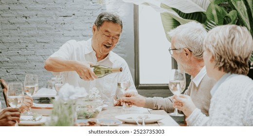 Asian man pouring wine for an retired couple. Man pouring wine is smiling. The retired couple enjoys wine at a table. Wine and dining scene with friends. Diverse retired friends hanging out for lunch. - Powered by Shutterstock