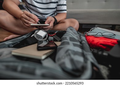 Asian Man Is Preparing Clothes In Suitcases. He's Choosing Clothes, Travel Documents, The Itinerary For A Solo Trip, And Check The Checklist. Travel, Holiday And Vacation Concept.
