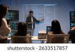 Asian man presents code using a projector during a software development meeting or coding workshop, guiding attendees through problem-solving and programming concepts in an educational setting.