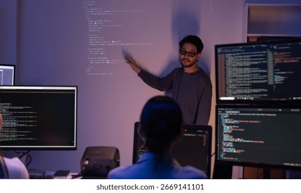 Asian man presents code using a projector during a software development meeting or coding workshop, guiding attendees through problem-solving and programming concepts in an educational setting.