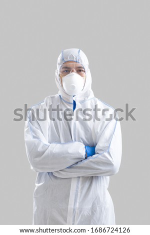Asian man in protective suit, glasses and gloves with crossed arms