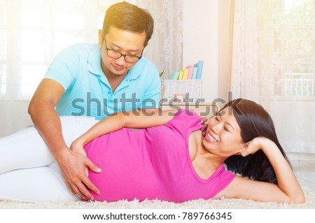 Asian man put his hand on pregnant wife's stomach