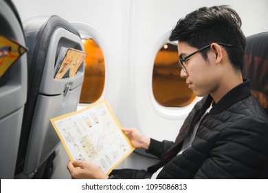 An Asian Man Reading Airplane Onboard Safety Information Suggestion Card