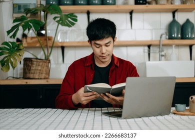 Asian man reading book while sitting at  in cafe or home office
 - Powered by Shutterstock