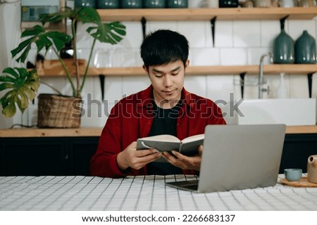Asian man reading book while sitting at  in cafe or home office