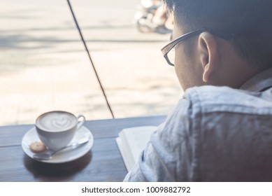 Asian Man Reading Books And Drinking Coffee