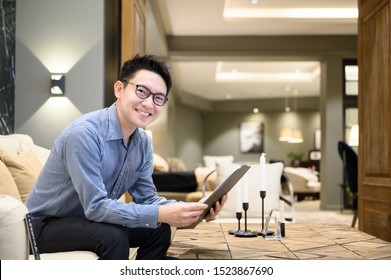 Asian Man Real Estate Agent Hands Holding Clipboard Document Sitting On Sofa In Example House