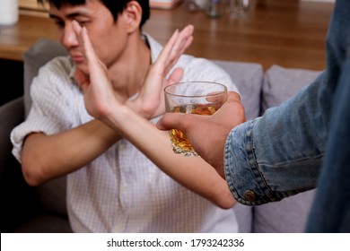Asian man refuse and say no to drink a alcohol by stopping hand sign as male alcoholism treatment of alcohol addiction and quit booze