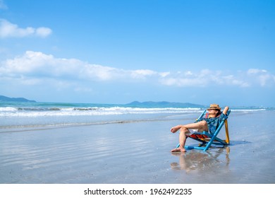 Asian Man Resting On Beach Chair At Tropical Beach. Happy Guy Sunbath Or Nap On Sunbed By The Sea In Sunny Day. Young Man Relax And Enjoy Beach Outdoor Activity Lifestyle On Summer Holiday Vacation