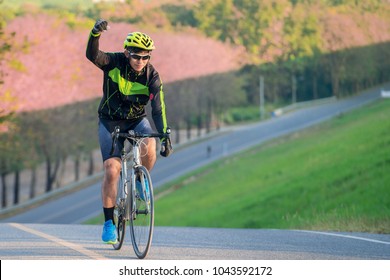 Asian man ride a bicycle on the road with nature background and finish this target to go to top of mountain, this immage can use for sport, relax, holiday, travel, exercise and fitness concept