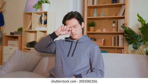 asian man rubbing his eyes by hands in the living room at home