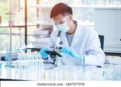 Asian Man Scientist Researcher Using Microscope In Laboratory. Medical Healthcare Technology And Pharmaceutical Research And Development Concept.