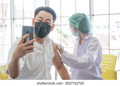 Asian Man Selfie By Phone At While Getting Covid Vaccine In Hospital, With Hand Nurse Injecting Vaccine. People With Smartphone For Social Media Networks Of Self-presentation And Expression.