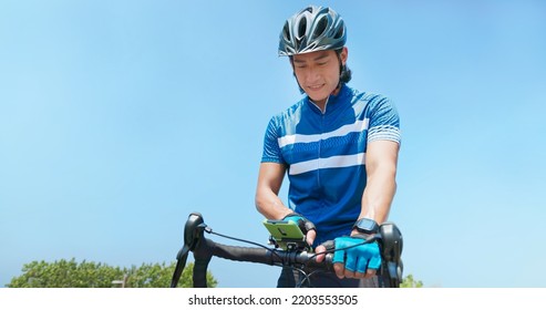 Asian Man Setting The Phone Going To Ride A Bicycle On Countryside Happily